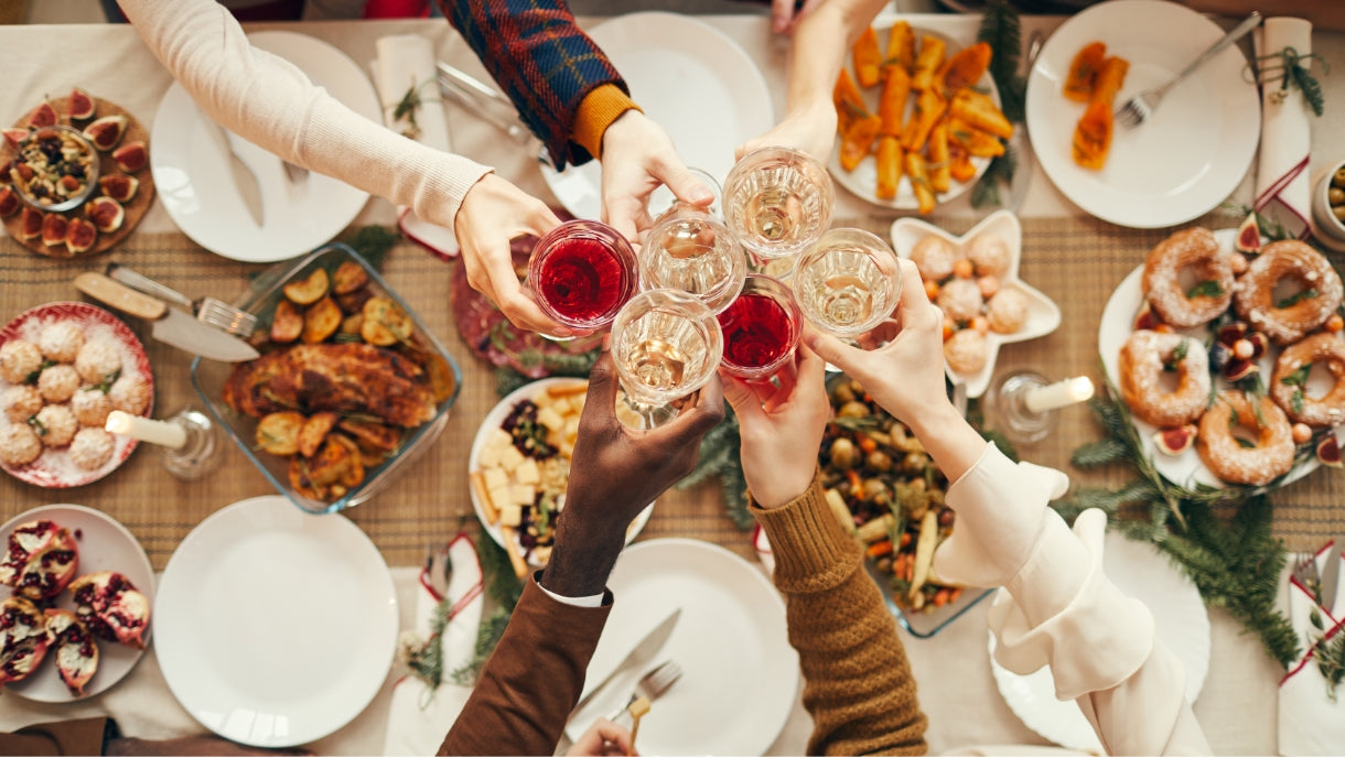 a vertical view of 6 guests toasting over a beautiful holiday meal