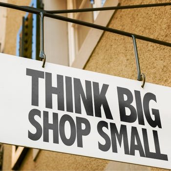 photo of a building sign that says 'think big shop small' in black block letters